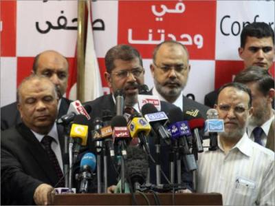 فيديو.. مرسي يرفع إشارة رابعة في وجه قاضيه ويعلن أنا هنا بالقوة 