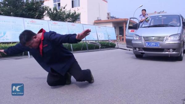  “فيديو”:  صيني يسير بحذاء وزنه 300 كيلو جرام ويسحب سيارة برقبته!